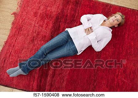 Stock Photo - Young woman lying on a red carpet. Fotosearch