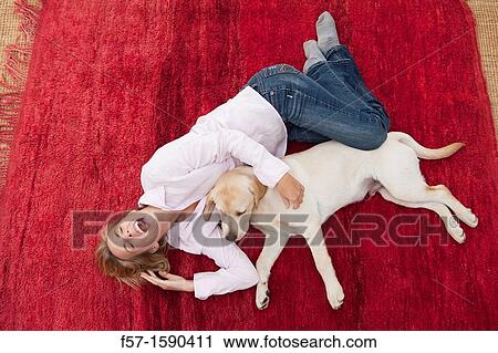 Young woman lying on a red carpet with her dog View Large Photo Image Stock Image - Young woman lying on a red carpet with her dog. Fotosearch