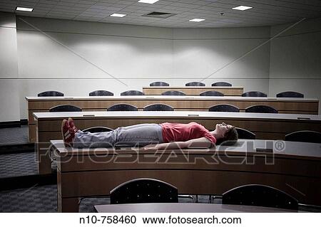 Young woman lying on a table in an empty college classroom. View Large Photo Image Stock Image - Young woman lying on a table in an empty college classroom.. Fotosearch