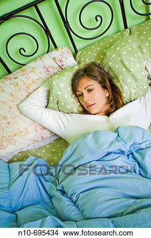 Picture - Young woman lying on her bed.. Fotosearch