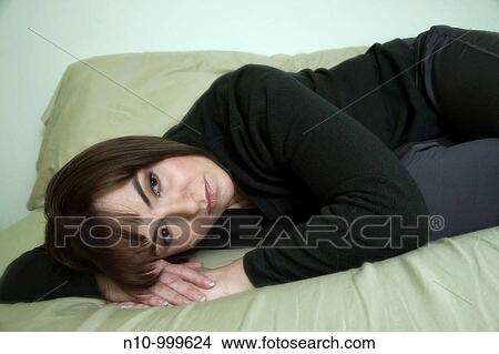 Young woman lying on her bed View Large Photo Image Picture - Young woman lying on her bed. Fotosearch