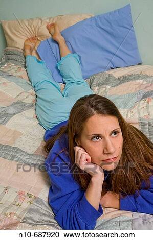 Young woman lying on her bed. View Large Photo Image Stock Image - Young woman lying on her bed.. Fotosearch