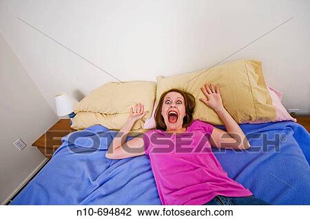 Stock Image - Young woman lying on her bed. Fotosearch