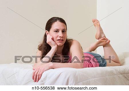 Young woman lying on her bed. View Large Photo Image Stock Photo - Young woman lying on her bed.. Fotosearch