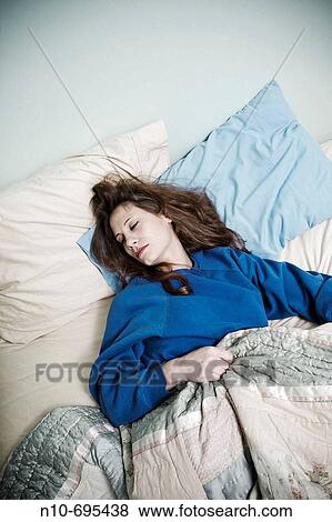 Young woman lying on her bed. View Large Photo Image Stock Photo - Young woman lying on her bed.. Fotosearch