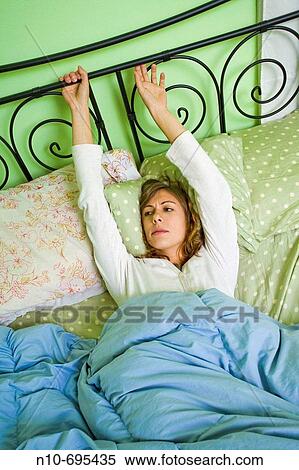 Stock Photography - Young woman lying on her bed.. Fotosearch