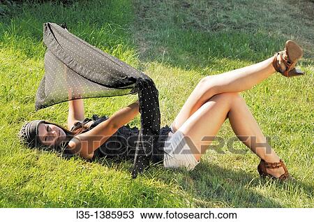 Young woman lying on the grass and playing with a cloth, summer, Germany View Large Photo Image Stock Image - Young woman lying on the grass and playing with a cloth, summer, Germany. Fotosearch