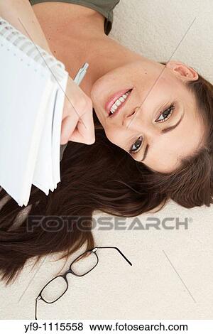 Stock Photo - Young woman lying writing.. Fotosearch