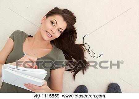 Stock Photo - Young woman lying writing.. Fotosearch