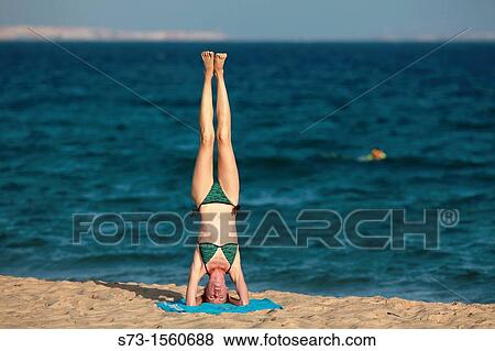 Stock Photo - Young woman making yoga in Tarifa beach, Cadiz, Andalusia. Fotosearch