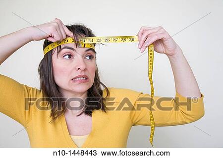 Young woman measuring the size of her head with a tape measure View Large Photo Image Stock Image - Young woman measuring the size of her head with a tape measure. Fotosearch