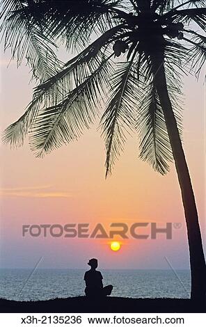 young woman meditating at sunset on top of cliff at Varkala, Thiruvananthapuram district, State of Kerala, India, South Asia. View Large Photo Image Stock Photograph - young woman meditating at sunset on top of cliff at Varkala, Thiruvananthapuram district, State of Kerala, India, South Asia.. Fotosearch