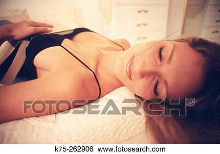 Young woman napping with book in bed View Large Photo Image Stock Photograph - Young woman napping with book in bed. Fotosearch