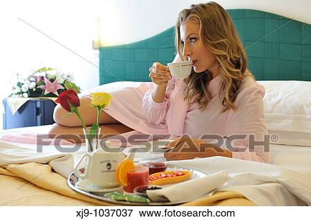 Stock Photo - Young woman on bed in hotel room. Fotosearch