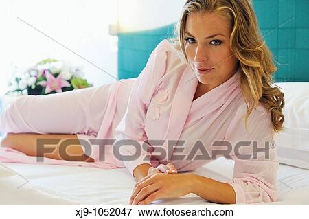 Stock Photo - Young woman on bed in hotel room. Fotosearch