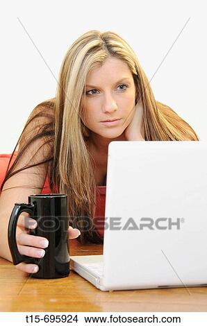 Young woman on computer having a cup of coffee in the morning View Large Photo Image Picture - Young woman on computer having a cup of coffee in the morning. Fotosearch
