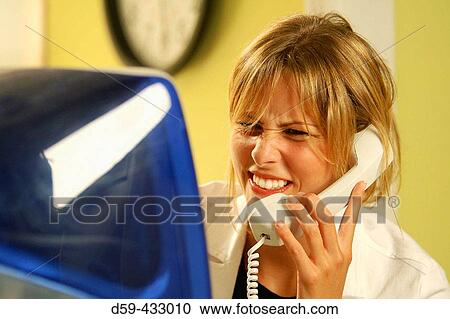 Young woman on phone, confused look, in front of computer. View Large Photo Image Stock Image - Young woman on phone, confused look, in front of computer.. Fotosearch