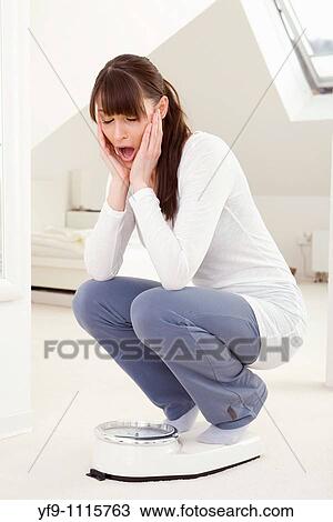Stock Image - Young woman on scale.. Fotosearch