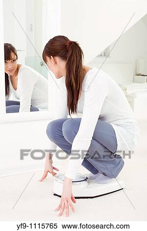 Stock Photography - Young woman on scale.. Fotosearch