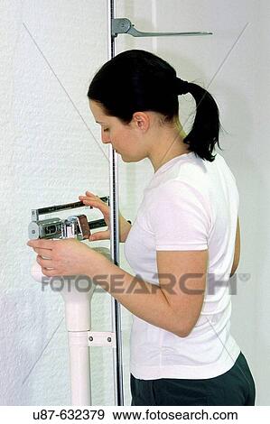 Stock Photo - Young woman on scales checking weight. Fotosearch