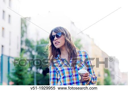 Stock Photography - Young woman on the street with takeaway coffee cup. Fotosearch