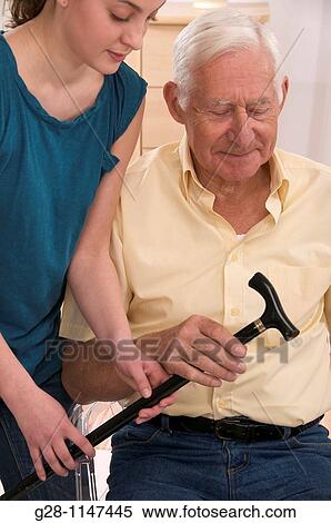Young woman or grand daughter helping a Senior man or grandfather to Hold his Walking stick View Large Photo Image Stock Photography - Young woman or grand daughter helping a Senior man or grandfather to Hold his Walking stick. Fotosearch