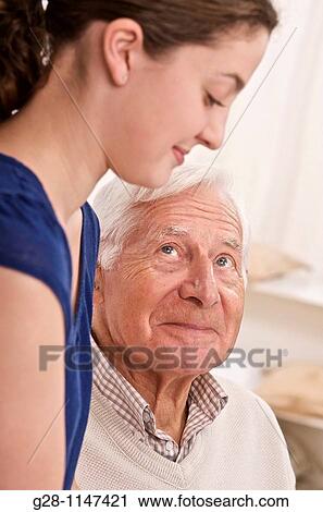 Stock Image - young woman, or grand daughter or home help comforting senior man. Fotosearch