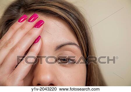 Stock Image - Young woman partially covering her face.. Fotosearch