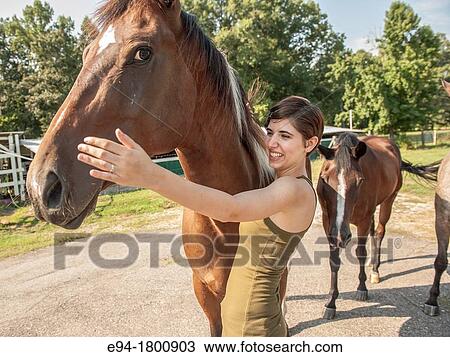 Stock Image - Young woman petting a horse. Fotosearch