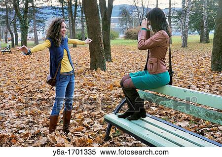 Young woman photographing her friend in park View Large Photo Image Stock Photography - Young woman photographing her friend in park. Fotosearch