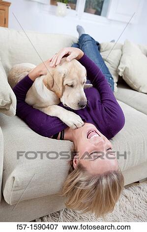 Young woman playing with her dog on the sofa View Large Photo Image Stock Photo - Young woman playing with her dog on the sofa. Fotosearch