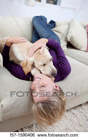 Young woman playing with her dog on the sofa View Large Photo Image Stock Photograph - Young woman playing with her dog on the sofa. Fotosearch