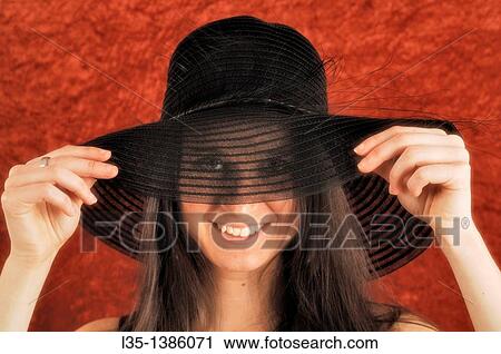 Stock Image - Young woman playing with old, transparent, hat. Fotosearch