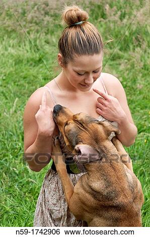 Stock Photograph - Young woman playing with pet dog. Fotosearch