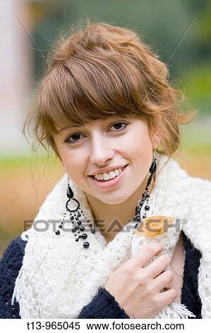 Stock Photography - Young woman portrait with a fallen Autumn leaf on her White scarf. Fotosearch