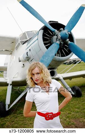 Stock Photography - Young woman poses front a old aeroplane. Fotosearch