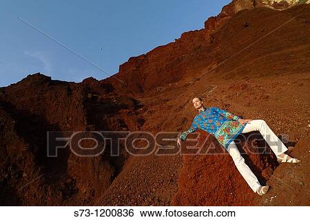 Stock Photograph - Young woman poses in the Red Beach in Santorini, Cyclades Islands, Greece. Fotosearch