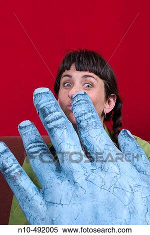 Stock Photography - Young woman posing behind a large sculpture of a hand. Fotosearch