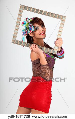 Stock Photo - Young woman posing happy through a special frame in the Studio. Fotosearch
