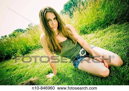 Young woman posing in front of tall grass at a park. View Large Photo Image Stock Image - Young woman posing in front of tall grass at a park.. Fotosearch