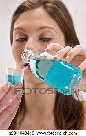 young woman pouring some mouthwash into a small glass for tooth hygiene in her bathroom View Large Photo Image Stock Photo - young woman pouring some mouthwash into a small glass for tooth hygiene in her bathroom. Fotosearch