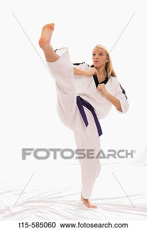 Stock Image - young woman practice a karate high kick. Fotosearch