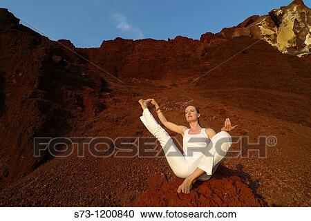 Stock Image - Young woman practicing yoga in the Red Beach in Santorini, Cyclades Islands, Greece. Fotosearch