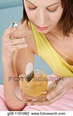 Young woman preparing tea or herbal tea with a tea bag in a transparent cup View Large Photo Image Stock Image - Young woman preparing tea or herbal tea with a tea bag in a transparent cup. Fotosearch