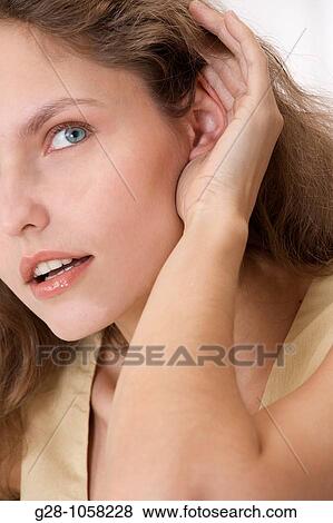 young woman putting herhand around her ear to hear better, or to listen to something View Large Photo Image Stock Photo - young woman putting herhand around her ear to hear better, or to listen to something. Fotosearch