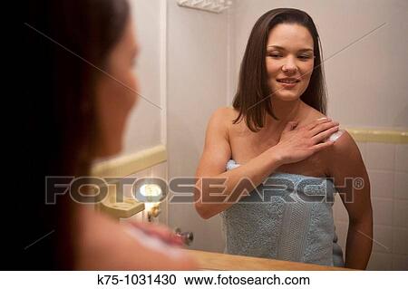 young woman putting on body lotion in mirror View Large Photo Image Stock Image - young woman putting on body lotion in mirror. Fotosearch