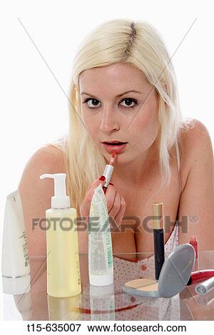Young woman putting on makeup applying lipstick, lip gross View Large Photo Image Stock Photo - Young woman putting on makeup applying lipstick, lip gross. Fotosearch