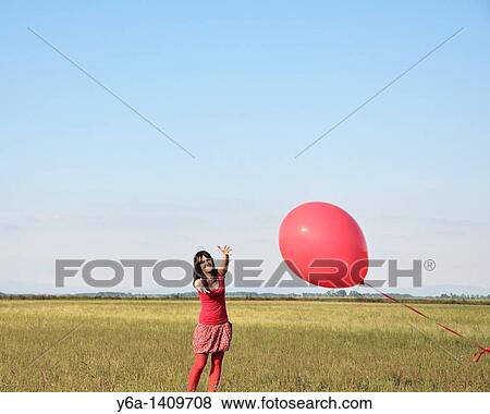 Young woman reaching for red balloon View Large Photo Image Stock Photo - Young woman reaching for red balloon. Fotosearch