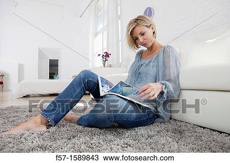 Young woman reading in her living room View Large Photo Image Stock Image - Young woman reading in her living room. Fotosearch