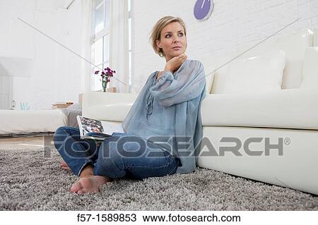 Young woman reading in her living room View Large Photo Image Stock Image - Young woman reading in her living room. Fotosearch